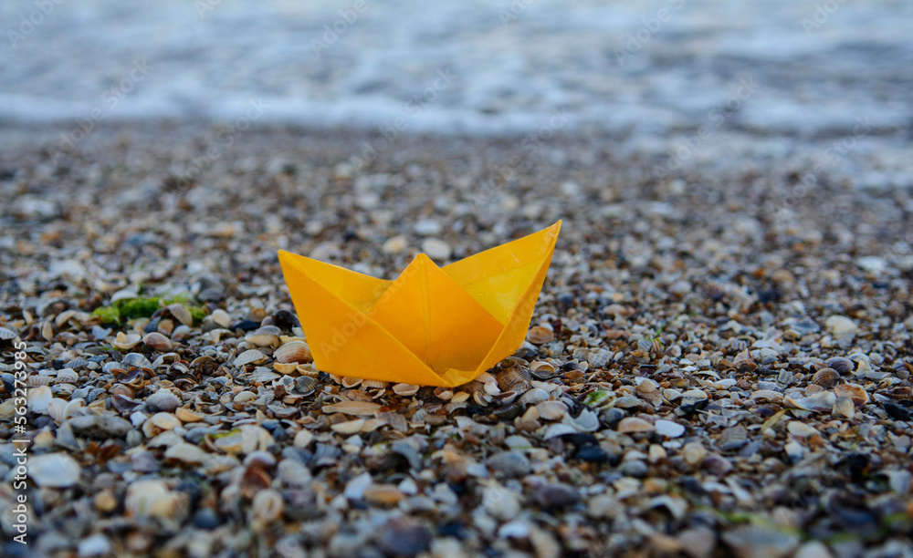Yellow paper boat on the sea. Ship on seashells. Free place Yellow paper boat on the sea. Ship on seashells. Free place