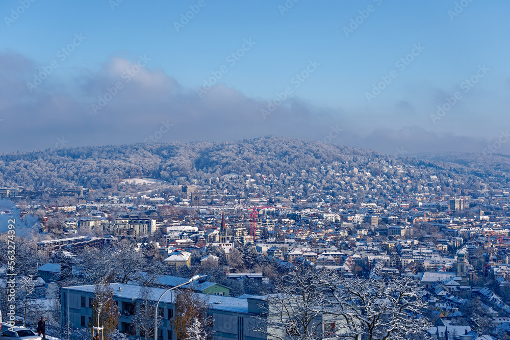 Scenic aerial view over snow covered City of Zürich with skyline and residential area on a blue cloudy late autumn day. Photo taken December 11th, 2022, Zurich, Switzerland.
