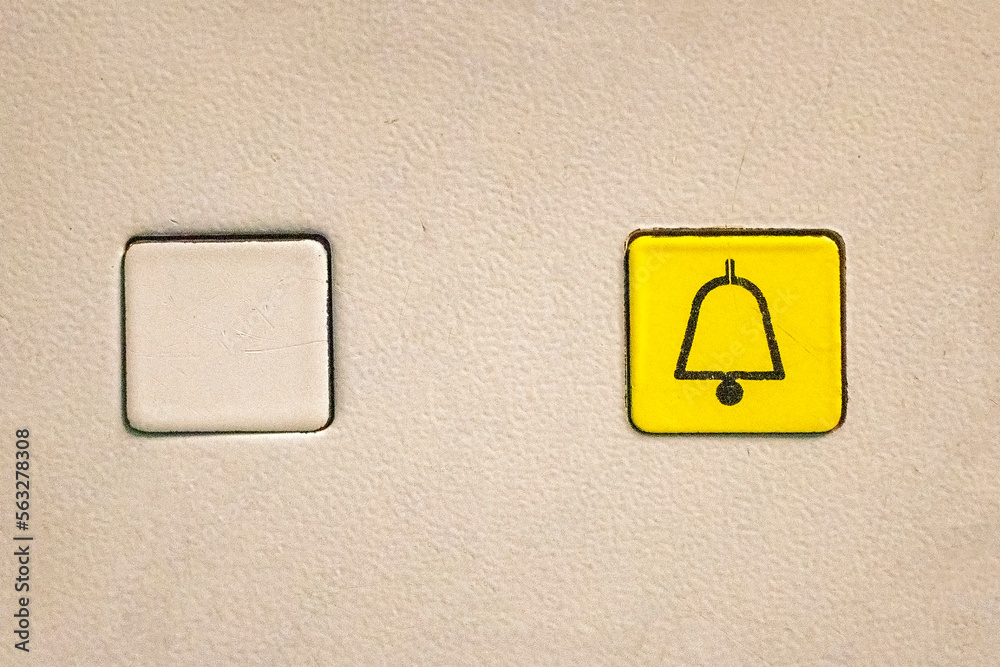 Empty elevator button and a yellow one with a bell icon for alarm