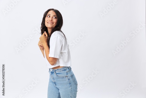 Woman in white t-shirt on white background brunette hands up gestures and signals poses in jeans emotion, lifestyle smiles, copy space