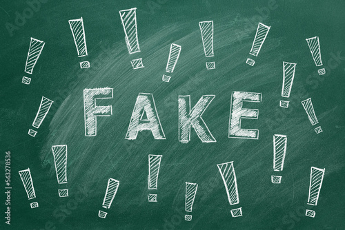 The word FAKE and exclamation marks written in chalk on a greenboard. Information and disinformation concept. Fake news. Hand drawn illustration.