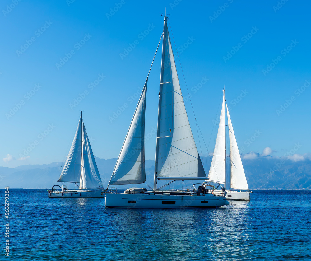 sailing yacht boats with white sails in blue sea , seascape of beautiful ships in sea gulf with mountain coast on background