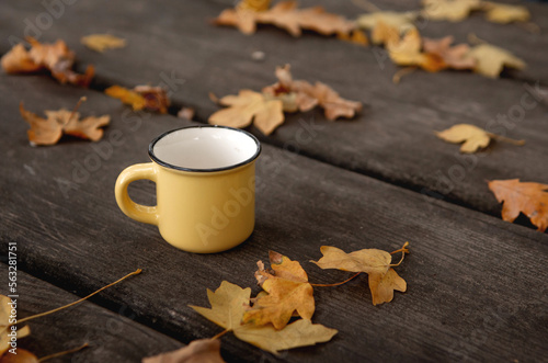 Close-up Small yellow cup on a wooden table. Autumn leaves. autumn