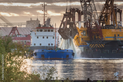 Dredging works in the seaport. The grab grabs the soil and loads it into the barge