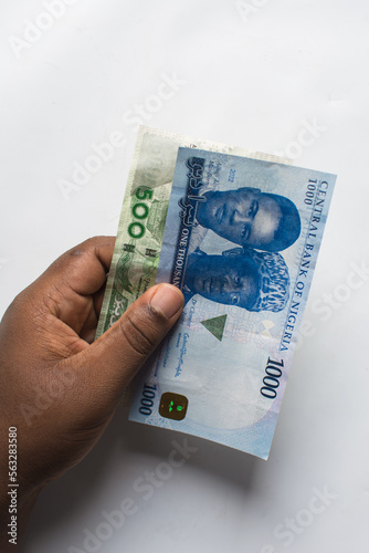 Hand holding the new Nigerian 1000 and 500 Naira notes on a white surface, Hand holding Nigeria's new currency	