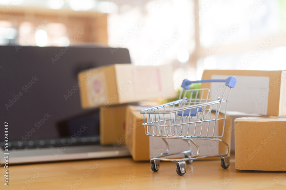 close up group of cart with wrapped boxes from online order with laptop on table in office room for delivery to worldwide customer for e-commerce shopping and logistic business concept