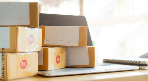 close up group of wrapped boxes from online order with laptop on table in office room for delivery to worldwide customer for e-commerce shopping and logistic business concept photo