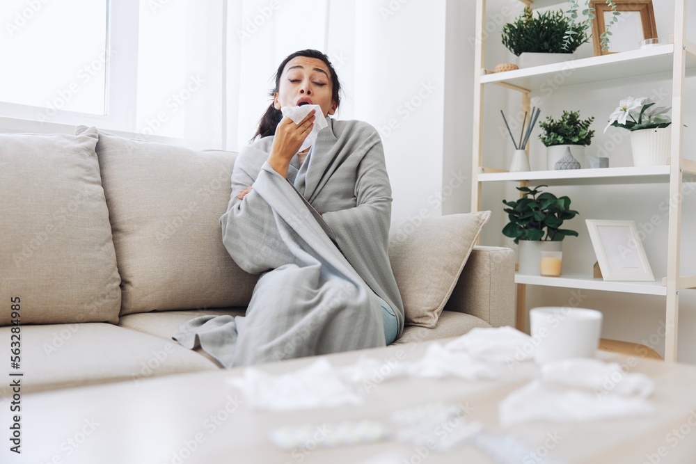 Woman cold headache runny nose and stuffy nose sitting on sofa in plaid, treatment for flu, allergies and covid-19