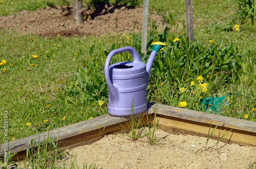 small plastic watering can in the garden © moskvich1977