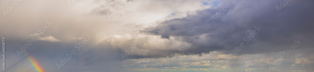Fototapeta premium sky with clouds after the rain with a rainbow. heavy cumulus clouds evening sky