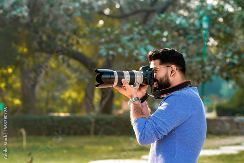 Foto Young indian man using camera equipment at park