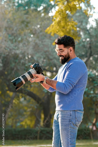 Young indian man using camera equipment at park