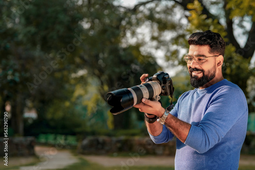 Young indian man using camera equipment at park