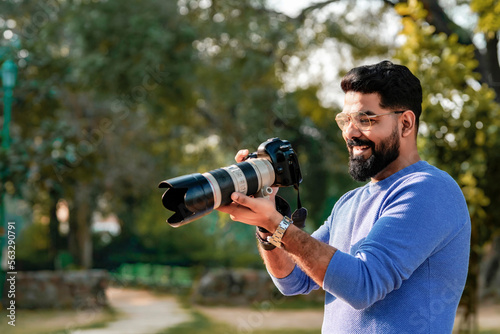 Young indian man using camera equipment at park