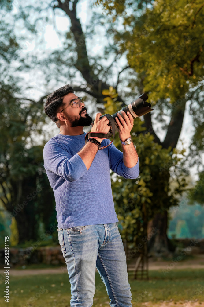 Young indian man using camera equipment at park