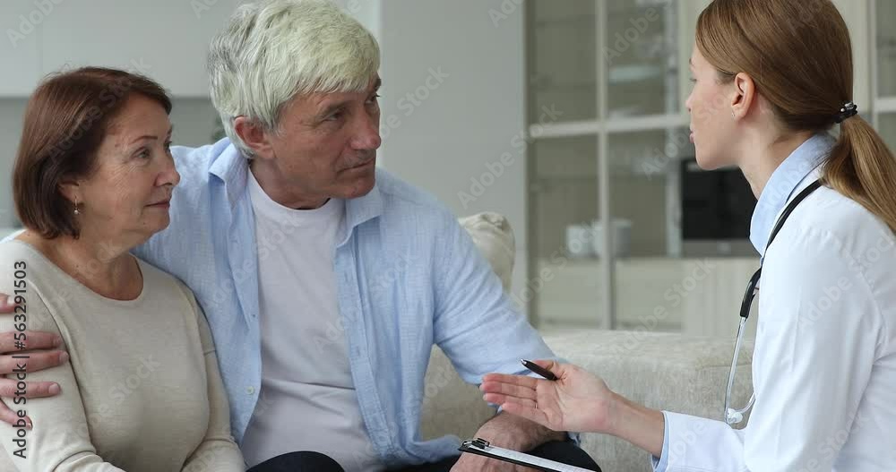Serious GP doctor woman visiting couple of elder patients at home ...