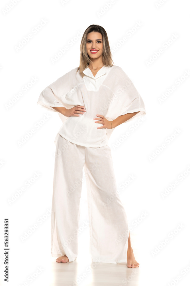 young modern barefeet smiling woman in white pants and blouse posing on white background. front view young modern barefeet smiling woman in white pants and blouse posing on white background. front view