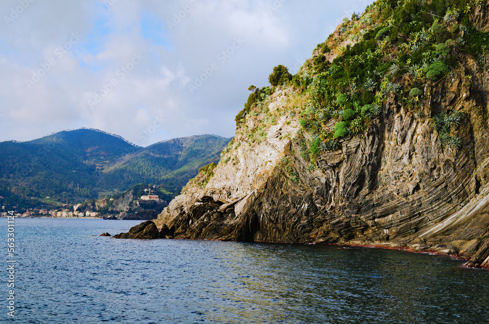 Scenic nature landscape view of beautiful rocks descend into the Ligurian Sea. Sea landscape with mountains covered by different plants, cacti and trees. Concept of landscape and nature