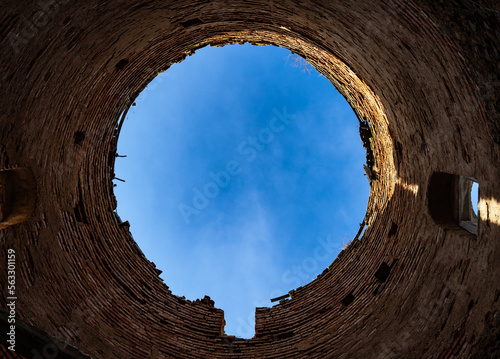 Stampa su tela View of the blue sky in the form of a circle from the bottom up inside a round tower of old brick