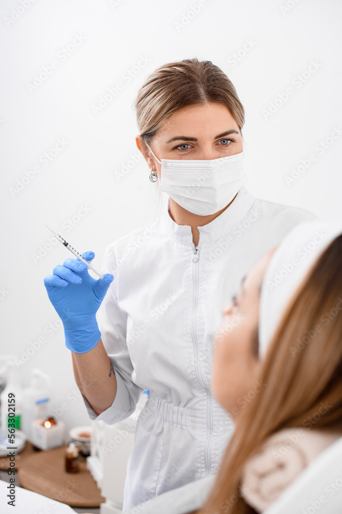 professional female doctor in mask with gloves on her hands holds a syringe with liquid professional female doctor in mask with gloves on her hands holds a syringe with liquid