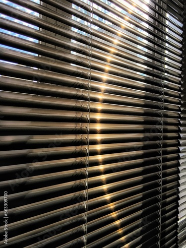 Aluminum blind on apartment window with sunlight reflection