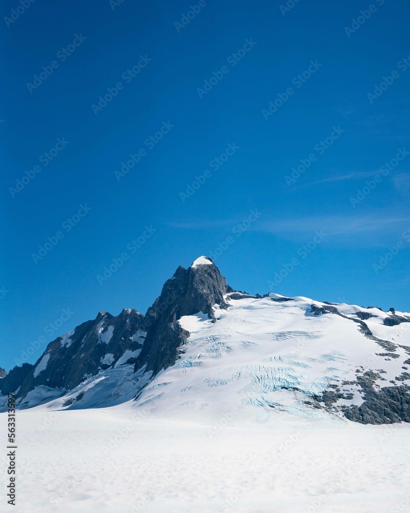 Obraz premium blue mountain peak during a bright sunny day covered in snow