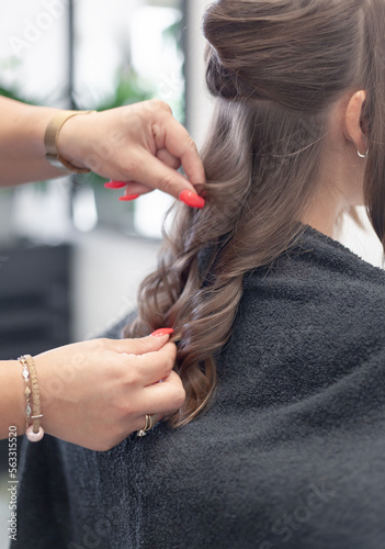 A close-up of hairstylist hands styling the client's hair