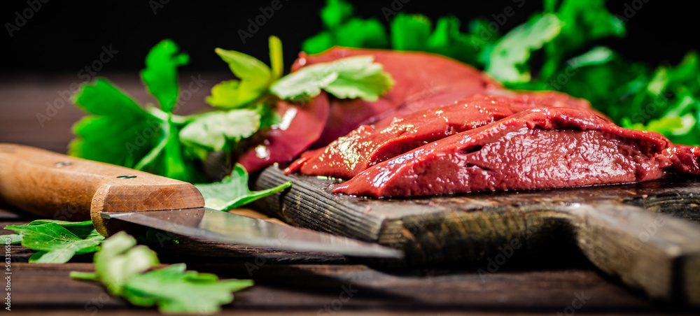 Raw liver on a cutting board with parsley. Raw liver on a cutting board with parsley.