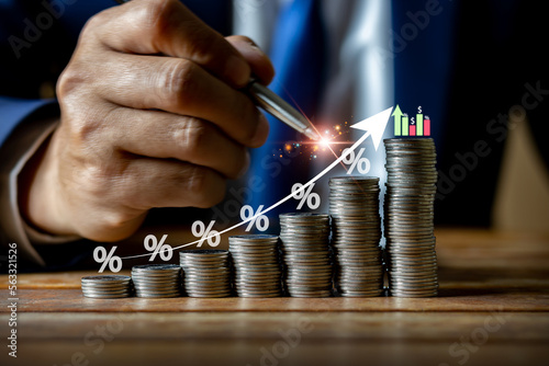 Businessman using pen touching money coin and showing candlestick symbol for financial figure investment increase savings interest rate or dividend investment business growth concept.