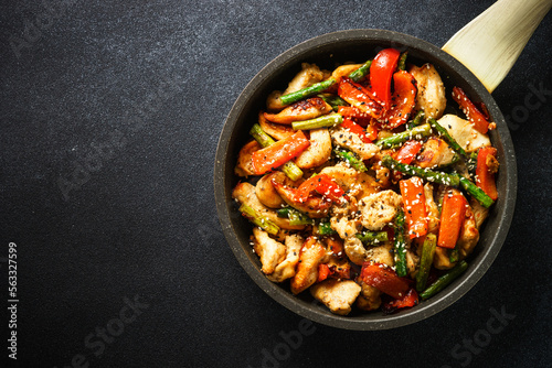 Chicken stir fry with vegetables at stone background. Top view with copy space.