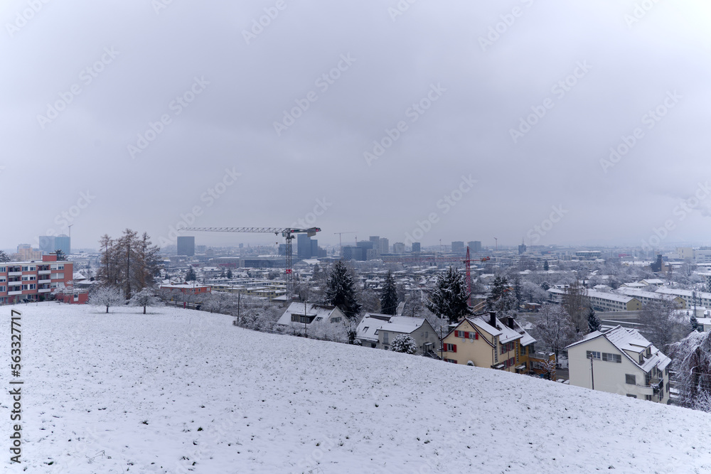 Aerial view over snow covered City of Zürich with skyline and gray cloudy winter sky on a snowy late autumn day. Photo taken December 17th, 2022, Zurich, Switzerland.