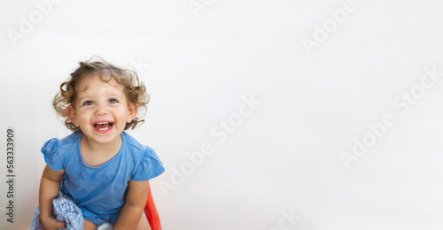 Portrait of a cute little white Caucasian girl with curly blonde hair, smiling and having fun, isolated against a pure white background