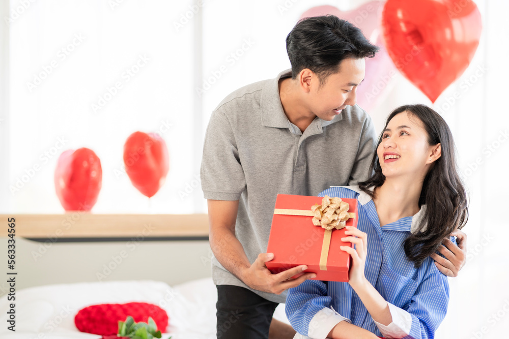 Asian couple Showing love surprise giving flowers or gifts to each other on important occasions such as Valentine's Day birthdays or wedding anniversaries with love and warmth in bedroom of their home Asian couple Showing love surprise giving flowers or gifts to each other on important occasions such as Valentine's Day birthdays or wedding anniversaries with love and warmth in bedroom of their home