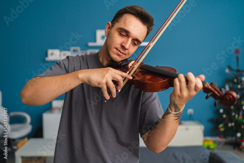 Fotografía A portrait of a young guy playing or learning a violin in his home private class