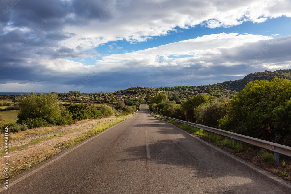 Scenic Road near a town by the Sea. Costa Rei, Sardinia, Italy. Sunny Cloudy Day. Scenic Road near a town by the Sea. Costa Rei, Sardinia, Italy. Sunny Cloudy Day.
