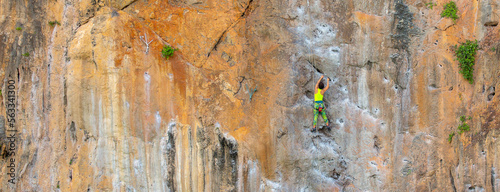 Valokuva A woman climber climbs a mountain along a steep cliff