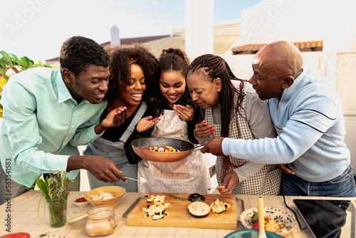 Happy African family preparing food recipe together on house patio photo