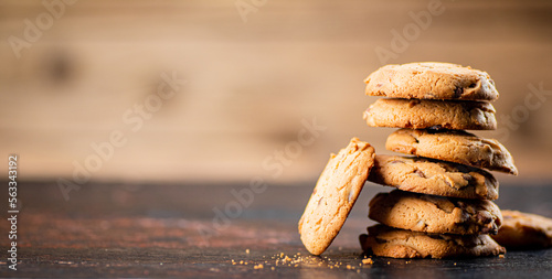 Pile of homemade cookies with pieces of milk chocolate on the table.