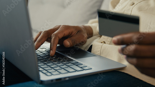 Close-up male hands man customer buyer holding credit card making purchase paying using banking electronic computer application in online store on laptop remote pay for delivery makes secure payment © Yuliia