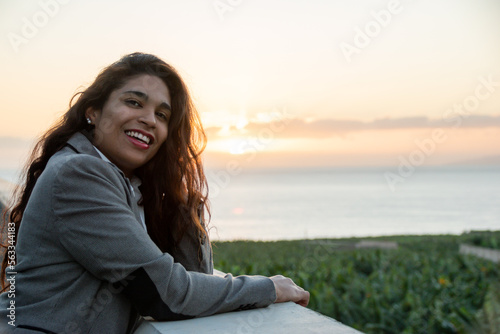 Smiling businesswoman enjoying the sunset from her office balcony. Copy space on the right. © Fénix Prods
