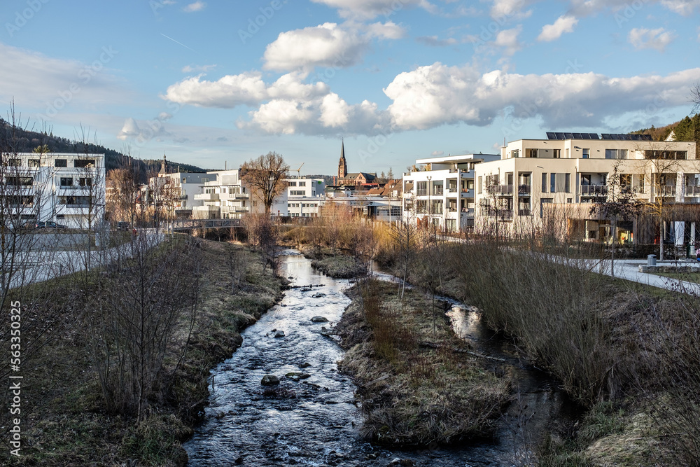 Moderne Wohnsiedlung an Fluß im Kontrast zu mittelalterlicher Kirche