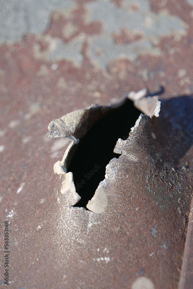 Hole in metal from a real missile explosion. After bombing. War in
