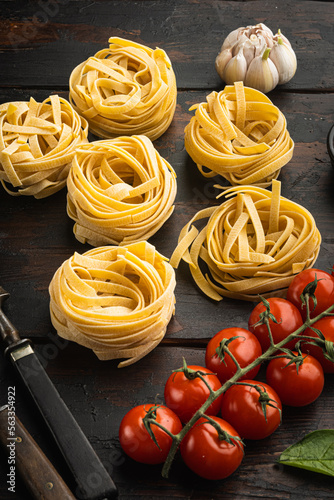 Fettuccine Tagliatelle pasta Italian food ingredients, on old dark wooden table background