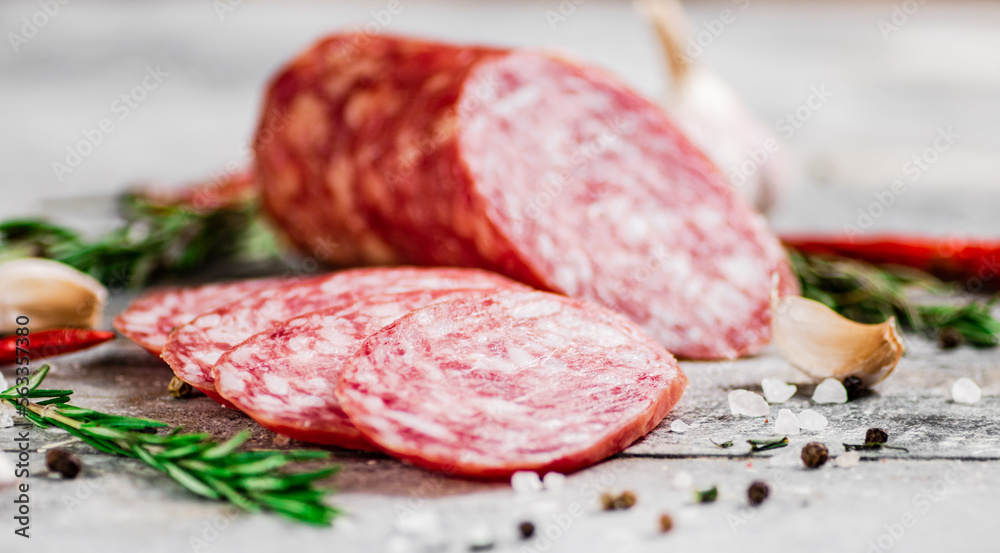 Pieces of salami sausage with spices, rosemary and chili peppers. 