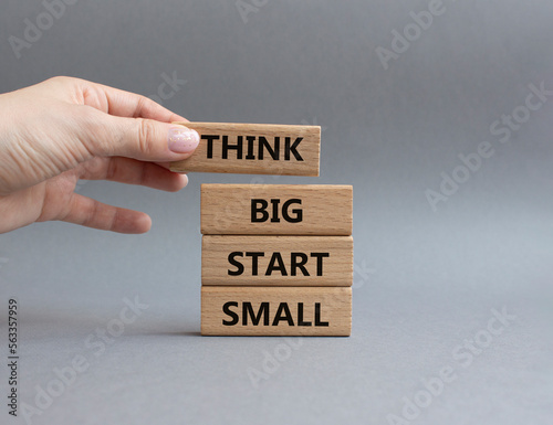 Think big start small symbol. Concept words Think big start small on wooden blocks. Beautiful grey background. Businessman hand. Business and Think big start small concept. Copy space