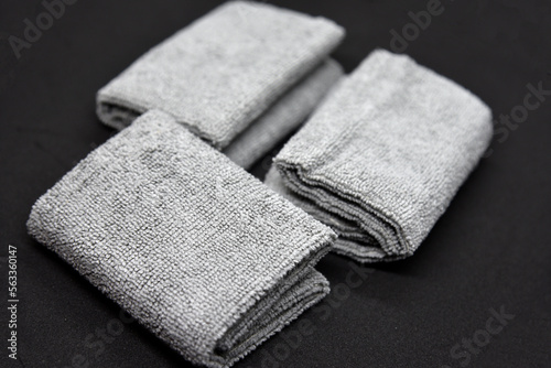 Three gray towels on a black background. Terry cloths for wiping furniture. Towels on a black background.