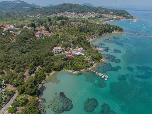 Fototapeta Naklejka Na Ścianę i Meble -  Aerial view of Notos Beach, Corfu Island. Greece. Bathers immersed in the crystal clear waters of the Greek coast. Coastline and houses and villas 