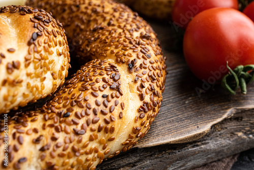 Simit or gevrek, traditional Turkish pastry food with breakfast ingredients olive and tomato cheese , on old dark wooden table background