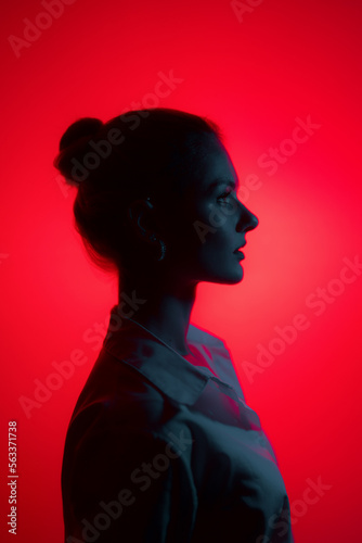 Dark woman profile portrait on red background with copy space. Lights play.