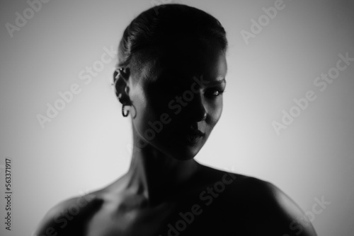 Creative woman black and white portrait with a shadow on her face. Soft glow on portions of skin.